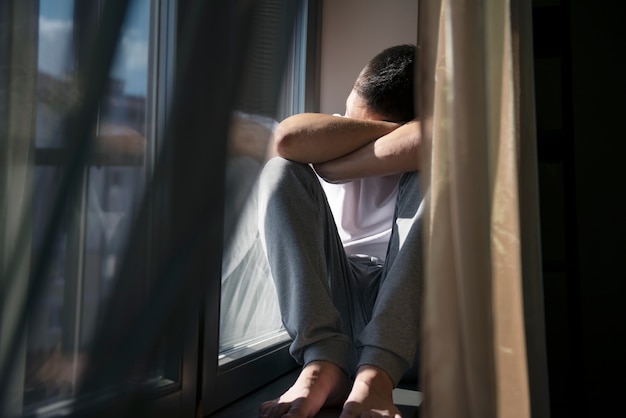 Foto gratuita retrato creativo del hombre con cortinas y sombras desde la ventana.