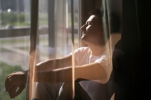 Retrato creativo del hombre con cortinas y sombras desde la ventana.