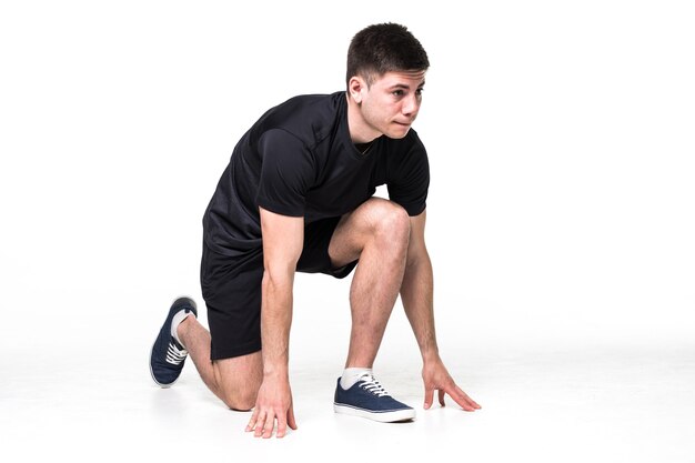 Retrato de cuerpo entero de un atleta masculino listo para correr aislado en la pared blanca