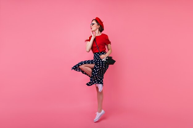 Retrato de cuerpo entero de una atractiva chica delgada. Maravillosa modelo femenina en boina y falda bailando.