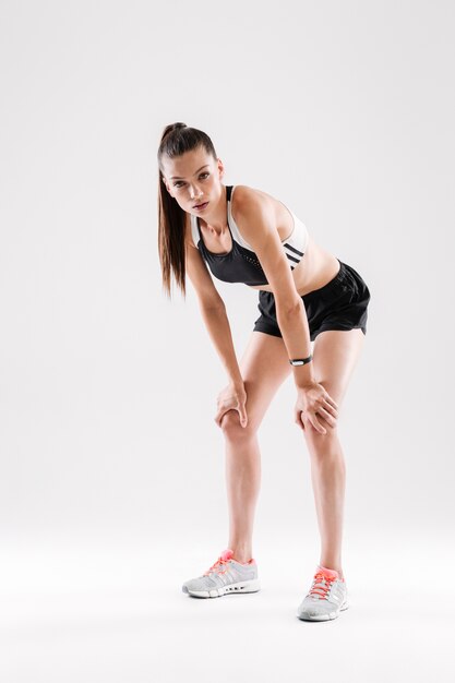 Retrato de cuerpo entero de una deportista cansada descansando mientras está de pie