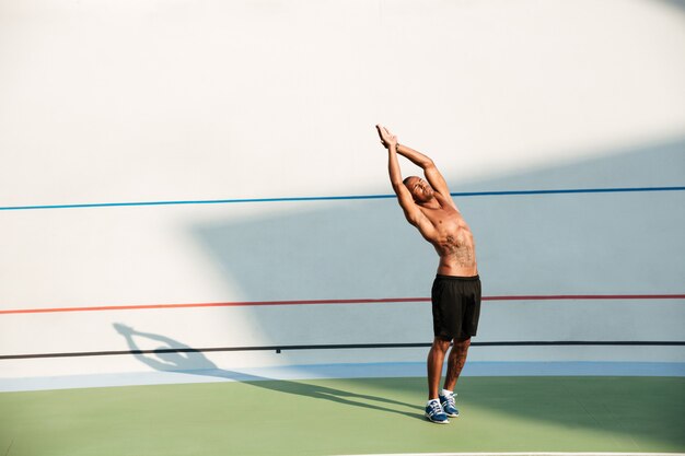 Retrato de cuerpo entero de un deportista concentrado haciendo estiramientos