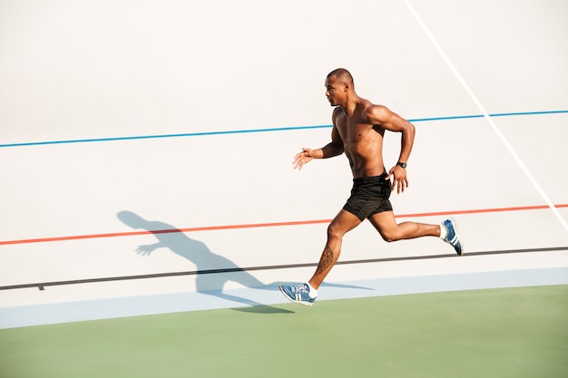 Retrato de cuerpo entero de un deportista medio desnudo fuerte corriendo