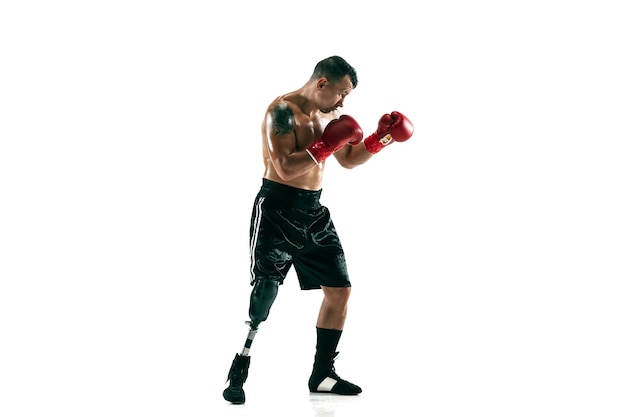 Retrato de cuerpo entero de deportista musculoso con prótesis de pierna, espacio de copia. Boxeador masculino en guantes rojos. Disparo aislado en la pared blanca.