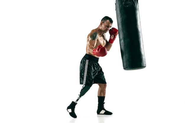 Retrato de cuerpo entero de deportista musculoso con prótesis de pierna, espacio de copia. Boxeador masculino en guantes rojos entrenando y practicando. Aislado en la pared blanca. Concepto de deporte, estilo de vida saludable.