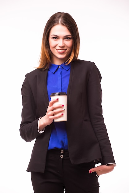 Retrato de cuerpo entero de una empresaria asiática sonriente que lleva una computadora portátil y una taza de café para llevar mientras está de pie aislado sobre una pared blanca