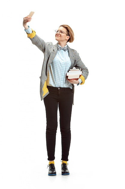 Retrato de cuerpo entero de una feliz estudiante sonriente sosteniendo libros aislados en espacio en blanco