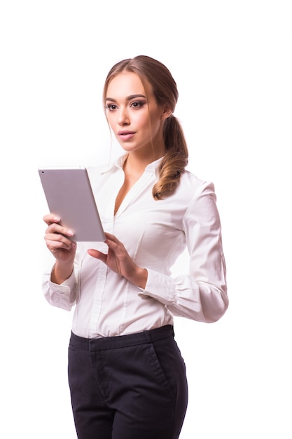 Retrato de cuerpo entero de la hermosa joven mujer de negocios en traje sosteniendo una tableta digital y sonriendo, en la pared gris