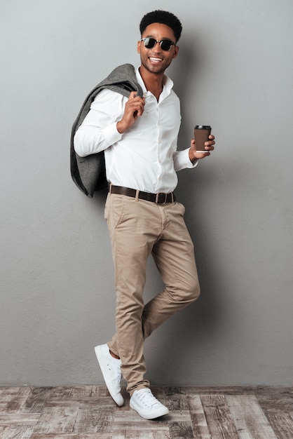 Retrato de cuerpo entero de un hombre africano sonriente en gafas de sol