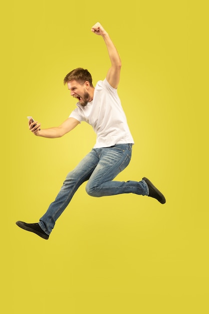 Retrato de cuerpo entero de hombre feliz saltando aislado en amarillo