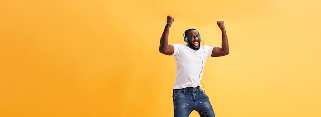 Retrato de cuerpo entero de un joven afroamericano cereza escuchando música con auriculares y d