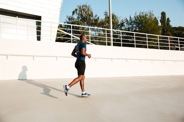 Retrato de cuerpo entero de un joven deportista africano en auriculares