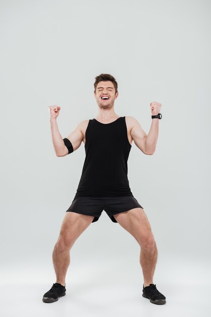 Retrato de cuerpo entero de un joven deportista feliz celebrando el éxito