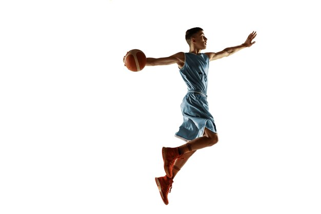 Retrato de cuerpo entero del joven jugador de baloncesto con una pelota aislada sobre fondo blanco de estudio. Adolescente entrenando y practicando en acción, movimiento. Concepto de deporte, movimiento, estilo de vida saludable, anuncio.