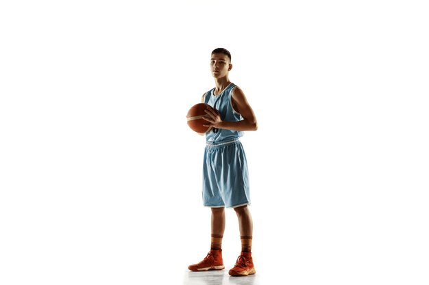Retrato de cuerpo entero del joven jugador de baloncesto con una pelota aislada sobre fondo blanco de estudio. Adolescente seguro posando con pelota. Concepto de deporte, movimiento, estilo de vida saludable, anuncio, acción, movimiento.