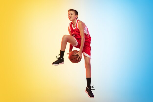 Retrato de cuerpo entero de un joven jugador de baloncesto con pelota en la pared degradada