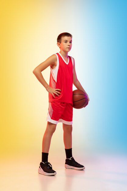 Retrato de cuerpo entero de un joven jugador de baloncesto con pelota en la pared degradada
