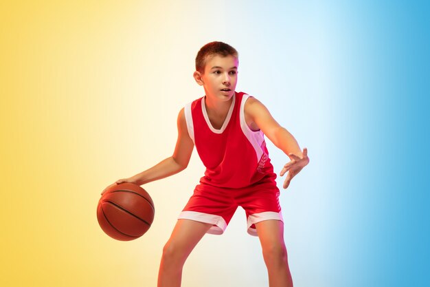 Retrato de cuerpo entero de un joven jugador de baloncesto con pelota en la pared degradada