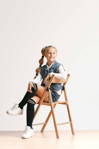 Retrato de cuerpo entero de lindo pequeño adolescente en ropa elegante jeans sonriendo