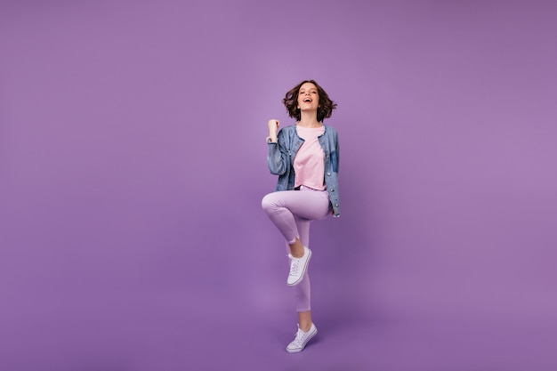 Retrato de cuerpo entero de mujer asombrosa complacida en zapatos blancos. Chica caucásica viste ropa casual bailando.