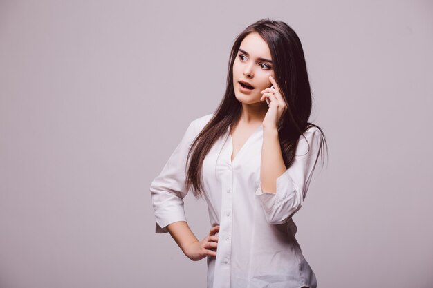 Retrato de cuerpo entero de una mujer joven feliz hablando por teléfono aislado sobre un fondo blanco.