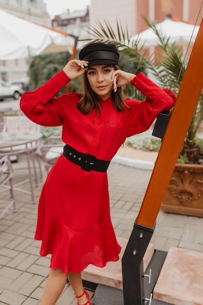 Retrato de cuerpo entero de la mujer parisina de moda en vestido de seda con cinturón de cuero negro. Chica con pestañas largas posando atractivamente