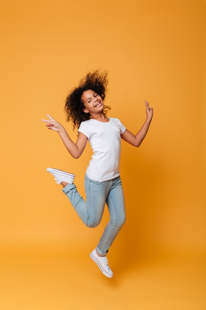 Retrato de cuerpo entero de una sonriente niña africana saltando