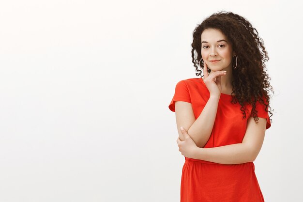 Retrato de curiosa estudiante encantadora en vestido rojo de moda