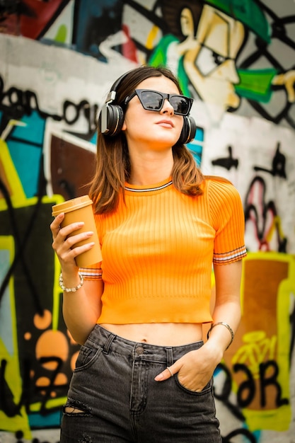 retrato, de, dama joven, llevando, auriculares, y, tenencia, taza de café