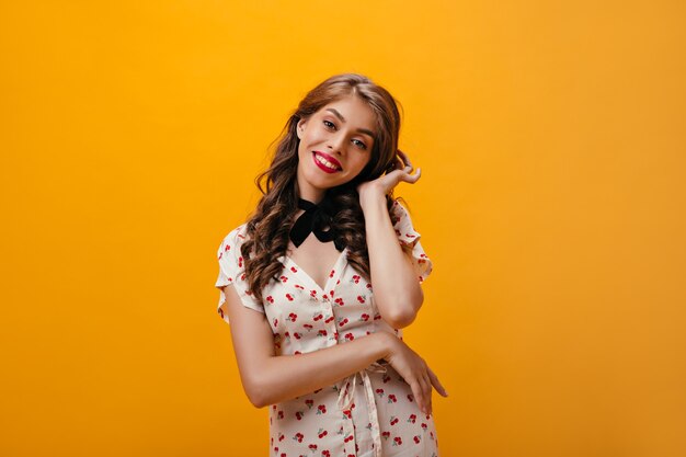 Retrato de dama rizada se viste con traje romántico. Hermosa mujer ondulada con labios rojos grandes en traje blanco sonriendo sobre fondo aislado.