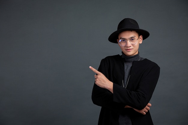 Retrato del dedo acusador modelo masculino y sonriendo en la pared oscura