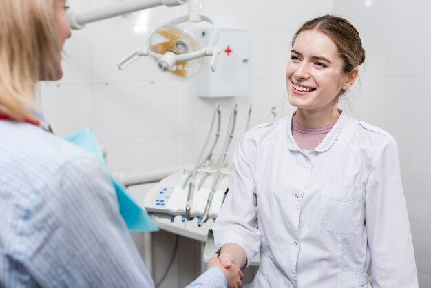 Retrato de dentista estrechándole la mano con paciente