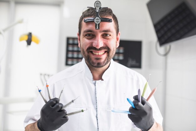 Retrato de un dentista feliz con diversas herramientas dentales