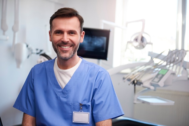 Foto gratuita retrato del dentista sonriente en el consultorio del dentista