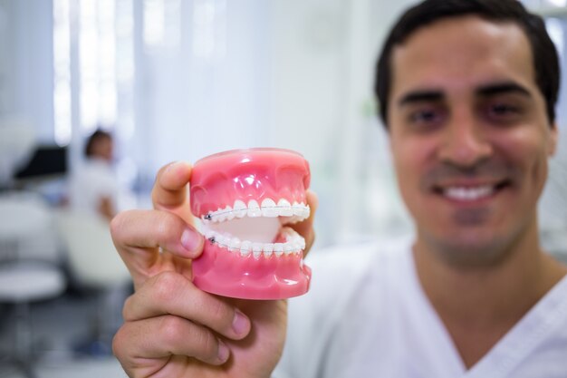 Retrato de dentista sosteniendo un conjunto de prótesis