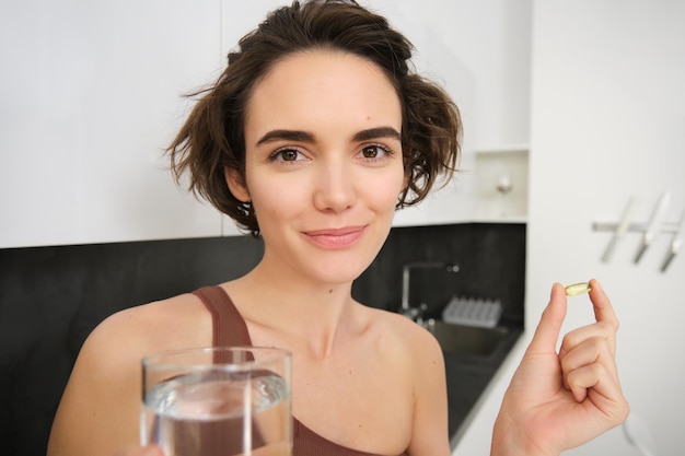 Retrato de una deportista bebiendo agua tomando vitaminas y suplementos dietéticos para tener una piel sana