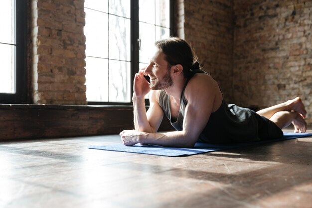 Retrato de un deportista sano feliz hablando por teléfono móvil