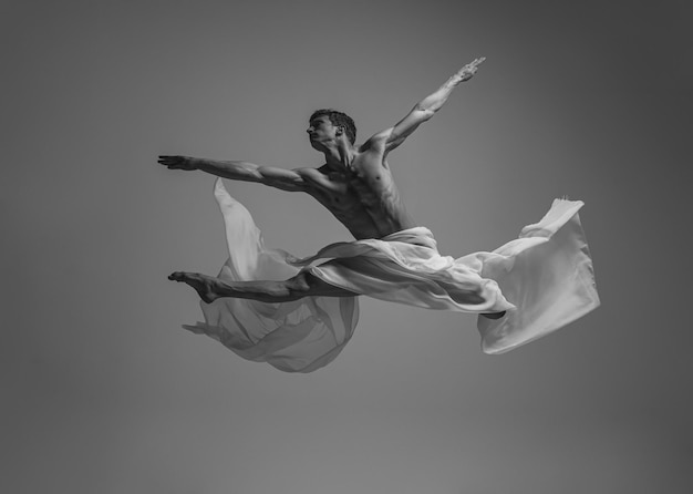 Retrato dinámico del bailarín de ballet profesional hombre actuando con tela estilo fotográfico en blanco y negro
