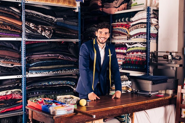 Retrato de un diseñador de moda masculino joven sonriente que mira la cámara en su tienda