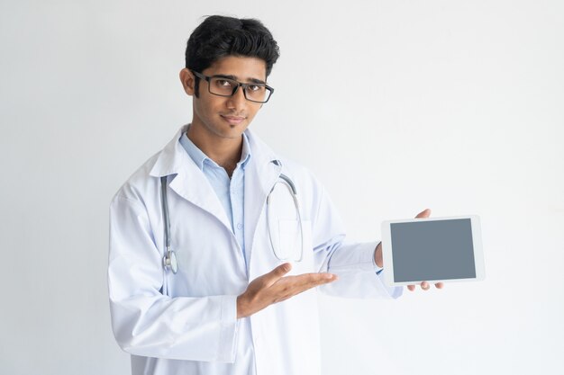 Retrato del doctor confidente joven que hace publicidad de la tableta.