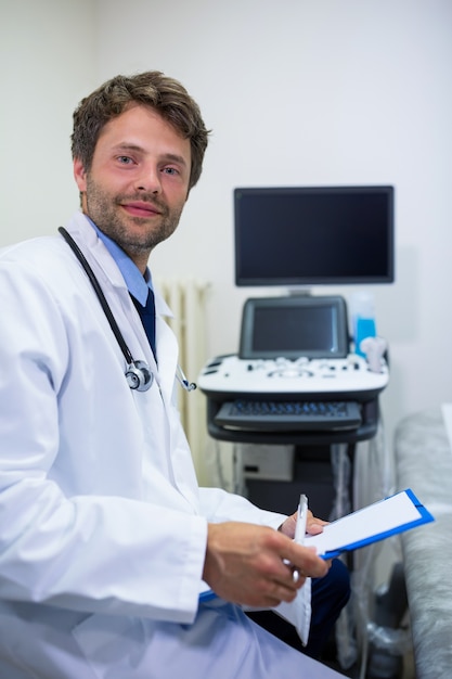 Retrato del doctor sonriente que sostiene el sujetapapeles