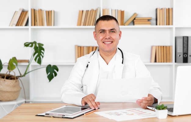 Retrato del doctor sonriente sentado en el escritorio