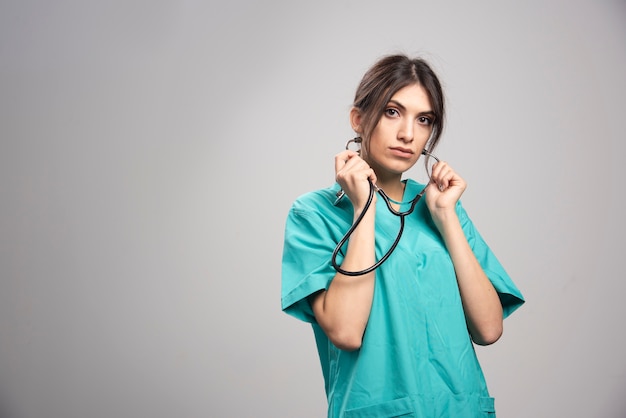 Retrato de doctora posando con estetoscopio en gris