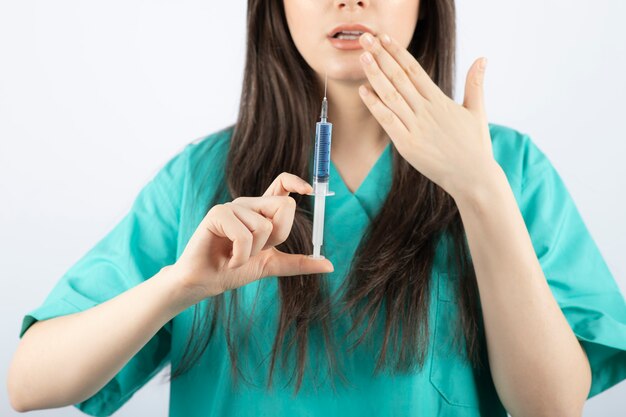 Retrato de doctora sosteniendo una jeringa grande. .