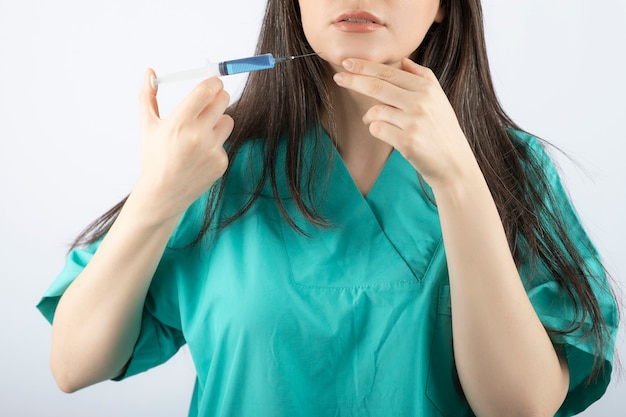 Retrato de doctora sosteniendo una jeringa grande. .