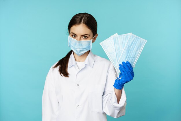 Retrato de una doctora trabajadora médica al sugerir máscaras faciales de la pandemia de covid de pie en hos...