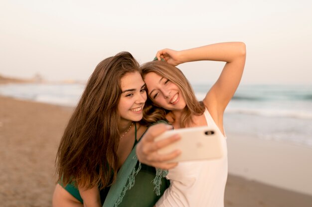 Retrato de dos adolescentes tomando autorretrato en el teléfono celular en la playa