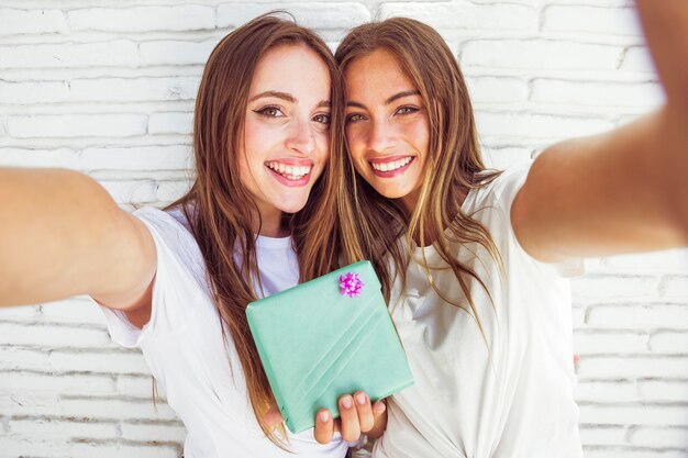 Retrato de dos amigas felices con caja de regalo