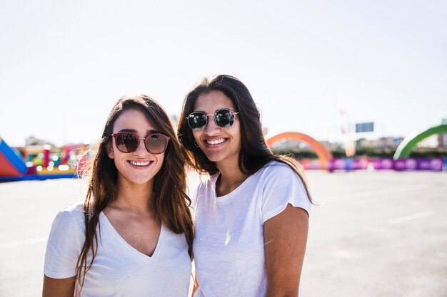 Retrato de dos amigas jóvenes con gafas de sol mirando a cámara