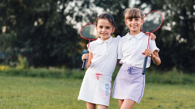 Retrato de dos amigas de pie con bádminton en el parque